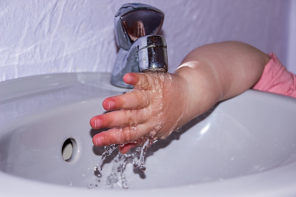 Pusotru gadu vecs zēns applaucē rokas un plaukstas ar karstu ūdeni